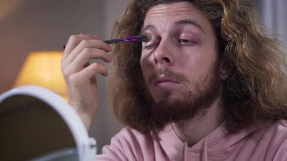 Bottom View of Caucasian Intersex Person Applying Eye Shadows. Bearded Man with Long Hair Doing