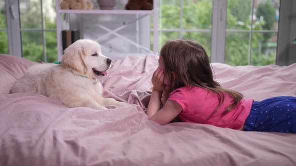 Little Girl Lying on Cozy Bed with Puppy