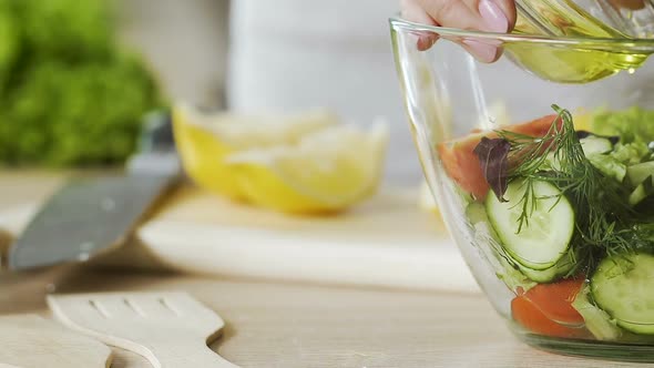 Lady dressing fresh salad with olive oil and stirring it in bowl, healthy eating