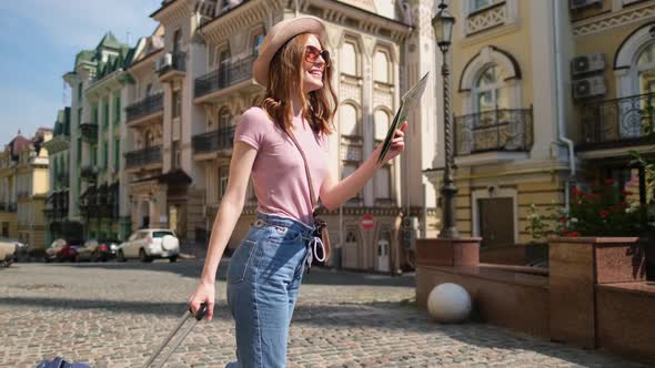 Beautiful Young Woman Tourist Pleasant with City Map and Suitcase in the City Center