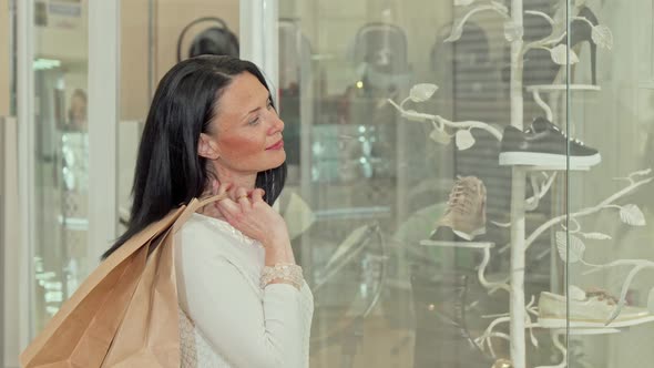 Beautiful Mature Woman Smiling To the Camera, While Examining Display of a Store