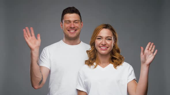 Couple in White T-shirts Waving Hands