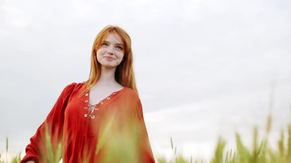 Slow Motion of Romantic Smiling Woman with Red Hair Redhead Girl Happy Walking Along Wheat Field on