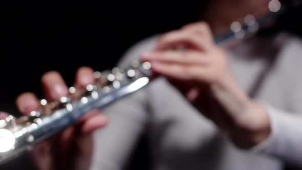 Closeup fingers of female musician playing melody on flute in studio. Female musician plays flute