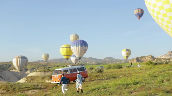 Women And Men Travelers Running To The Van And Air Balloons