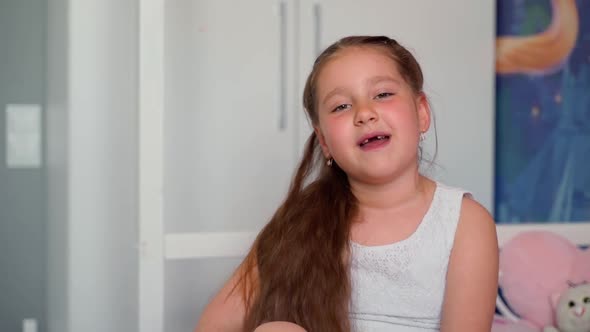 Slowmotion tooth girl looking at camera greeting sitting smiling at home