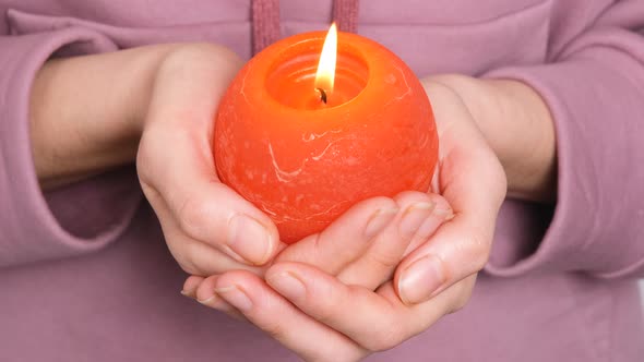 Woman or Girl Holding in Hands Red Round Burning Candle