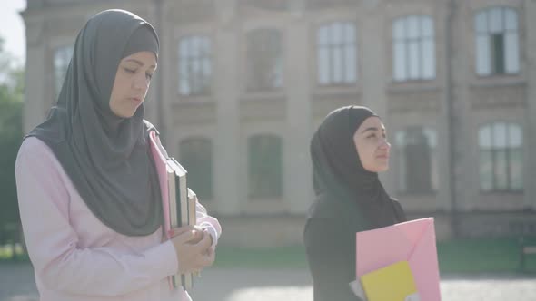 Side View Portrait of Two Muslim Immigrants Walking in Sunrays at the Background of European