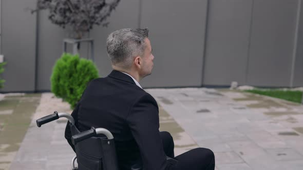 Crop View of Male Person in Suit Pushing Himself on Wheel Chair at Street