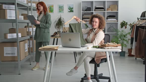 Online Store Smiling Female Manager Selling Clothes Via Video Link with Woman Preparing Goods for