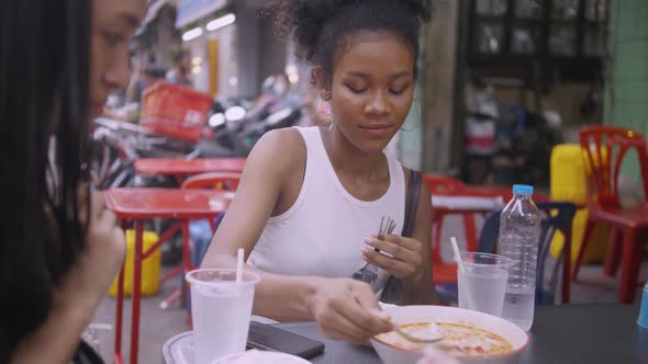 A girl enjoying street food with friends on Yaowarat Road or Chinatown in Bangkok, Thailand.