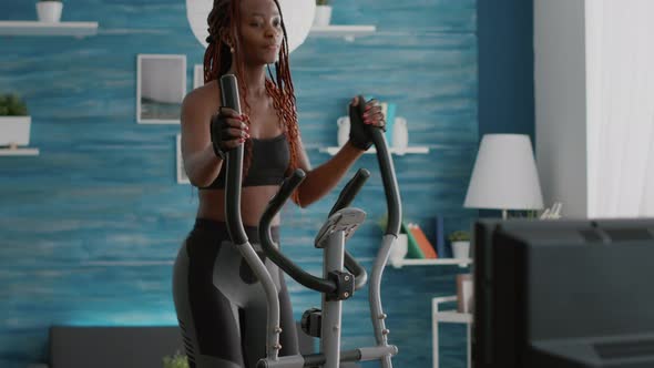 Fit Athletic Black Woman Running on Elliptical Bike Watching Wellness Routine