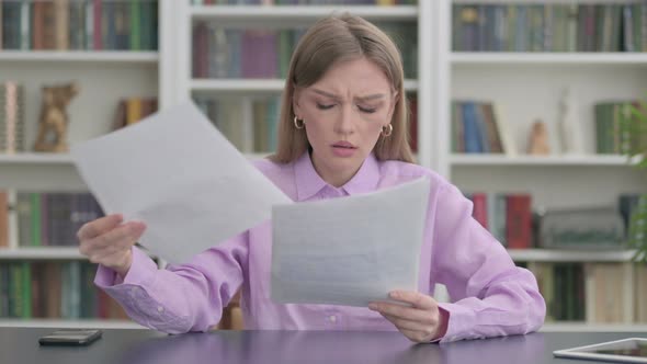 Woman Upset While Reading Documents in Office