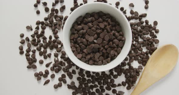 Video of overhead of bowl of chocolate chip with wooden spoon over white background