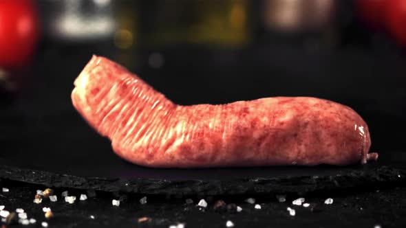 Super Slow Motion One Raw Sausage Falls on a Stone Board