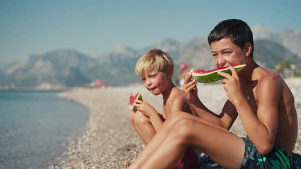 Happy Kids Eating Big Red Slices of Watermelon on the Beach