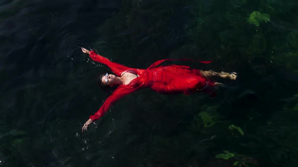 Woman in a Red Long Dress Is Lying on Her Back Bathing in the Green
