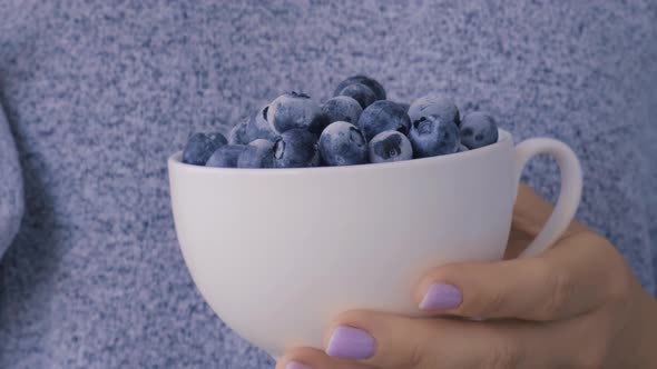 Woman Holding Bowl with Frozen Blueberry Fruits