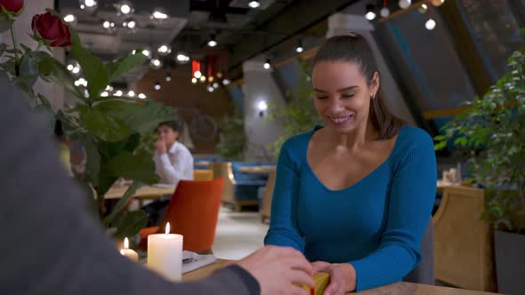 Portrait of a Beautiful Cute Young Girl Receives a Gift Box in a Romantic Atmosphere in a Restaurant