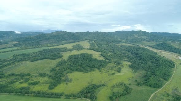 Aerial Drone View Beautiful Natural Scenery of Green Hills with Mountains in Background