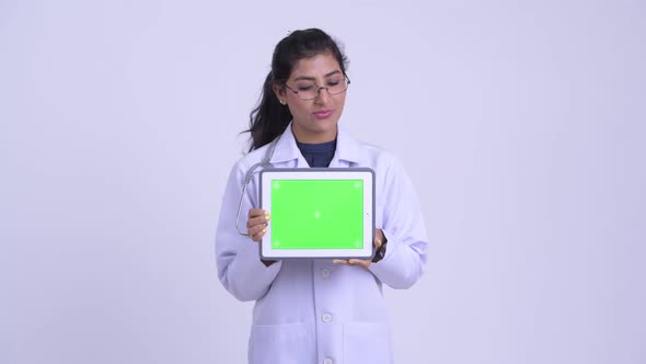 Young Happy Persian Woman Doctor Thinking While Showing Digital Tablet