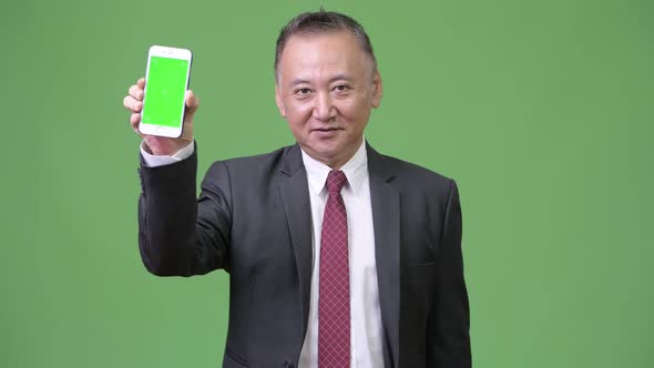 Mature Japanese Businessman Showing Phone To Camera