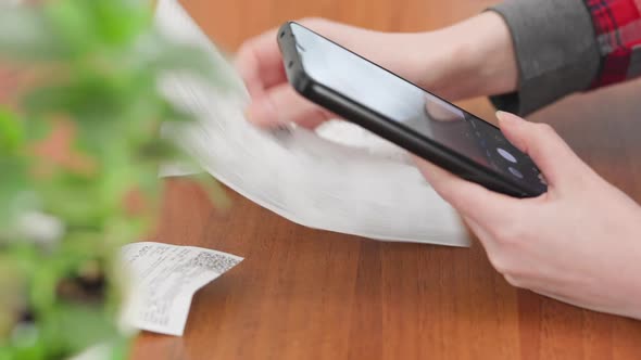 Woman scans the QR code on the receipts. Hands close-up. Home accounting and investments.