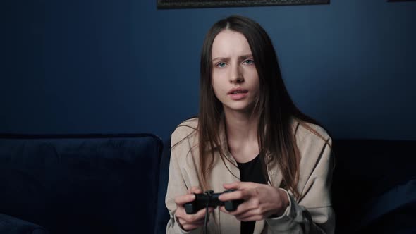 Woman Playing a Video Game at Home at Night, Excited Gamer Woman Sitting on a Couch, Playing