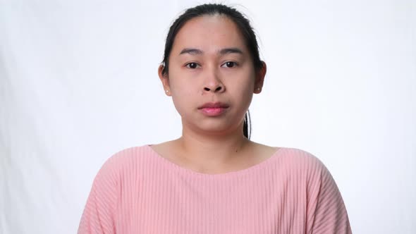 Angry Asian woman standing with arms crossed looking at camera on white background in studio