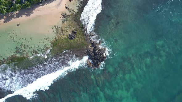 Cliff Between Ocean Waves Rolling on Green Sandy Coastline