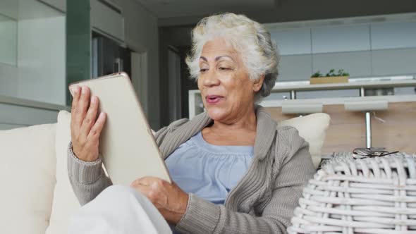 African american senior woman smiling while having a video call on digital tablet at home