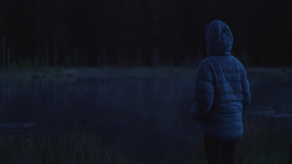 person watching a fog rolling over the lake at night, dark moody atmosphere