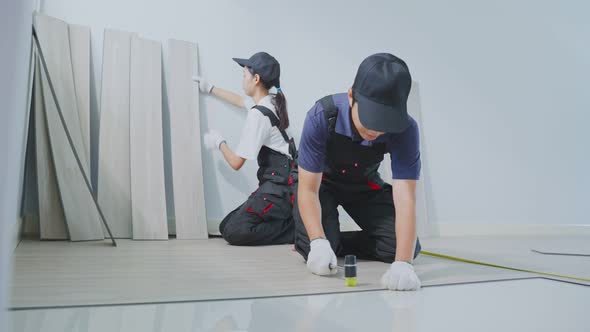 Asian Craftsman construction worker people installs laminate board on floor to renovate house.