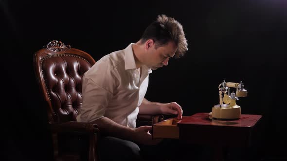 a Man on Black in a White Shirt Sits in a Chair