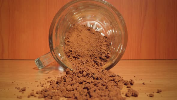 Instant Coffee Scattered on the Table in Front of the Glass Jar