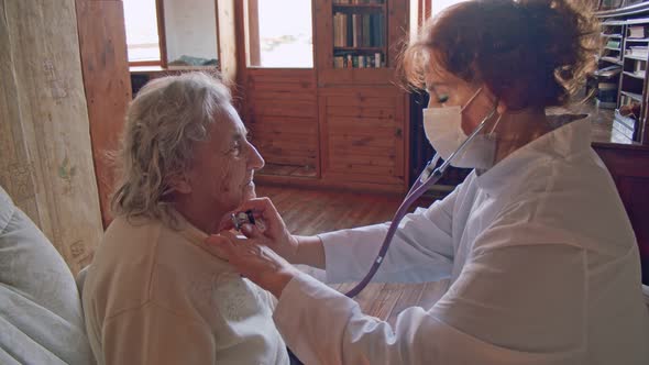 Female Doctor Use Stethoscope To Listen Heart of Elderly Woman Patient