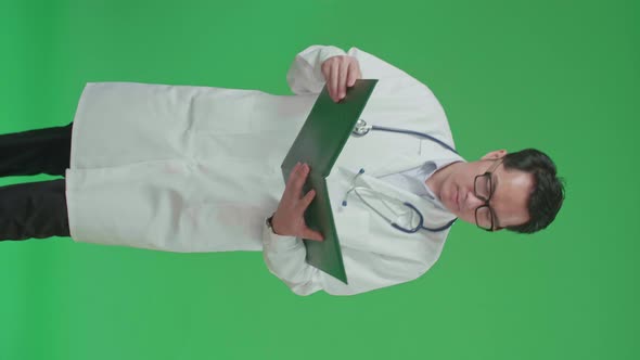 Asian Doctor With Stethoscope opening Document File And Reading While Walking On Green Screen