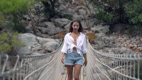 Long Haired Lady in Shorts and White Shirt Walks on Bridge