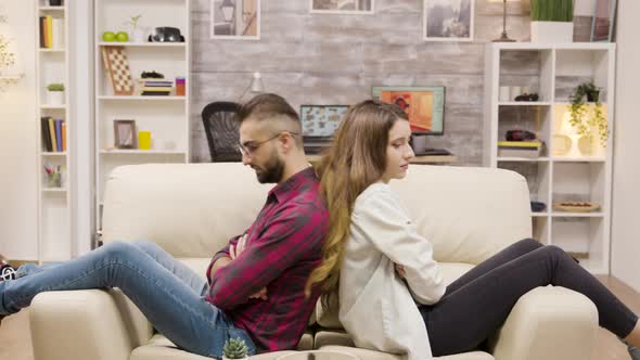 Couple Sitting Back To Back on the Couch with Arms Crossed