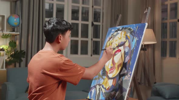 Side View Of An Asian Artist Man Holding Paintbrush Mixed Colour And Painting On The Canvas