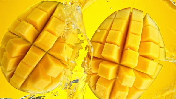 Super Slow Motion Shot of Mango Falling and Splashing Into Water on Yellow Background at 1000Fps