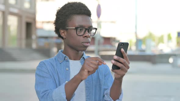 Upset Young African Man Reacting to Loss on Smartphone Outdoor