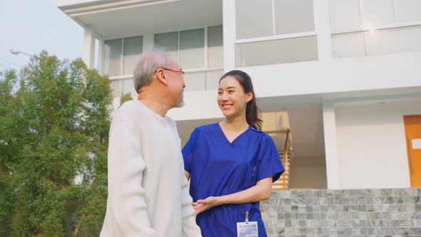 Portrait of Asian caregiver nurse support senior male walking outdoors.