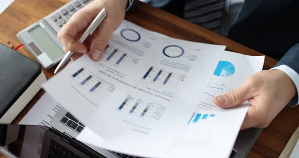 Businessman Examining Charts on Documents in Front of Laptop Closeup  Movie