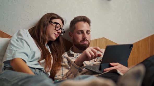 Young couple watching video on tablet in hotel room