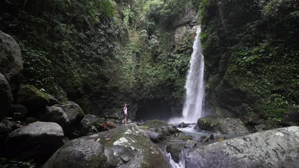 A Tourist Backpacker Amazed By the View of Wonderful Waterfall in the Forest