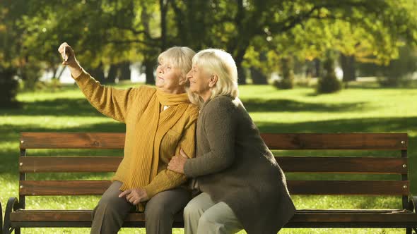 Two Old Ladies Taking Selfie on Mobile Phone Sitting on Bench in Park Technology