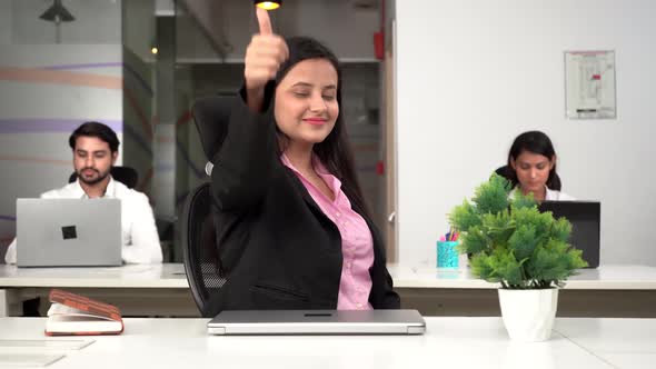 Indian successful businesswomen showing thumbs up to the camera in office space