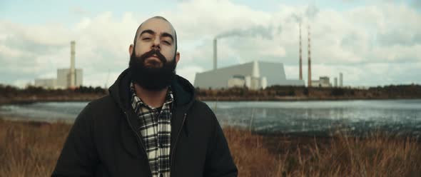 Man stands infront of lake and factory