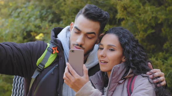 Multiracial Couple of Young Newlyweds Walking in Autumn Forest Making Video Call Using Smartphone